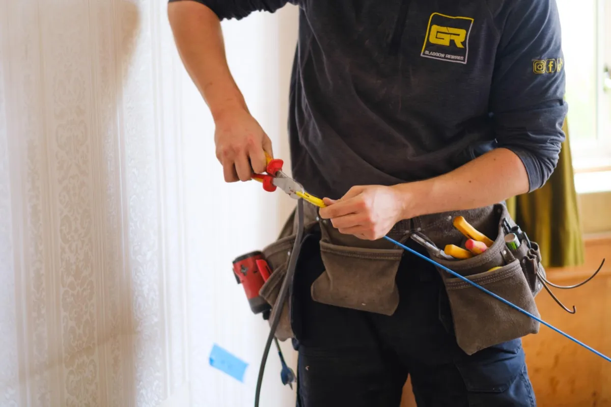 Electrician cutting channels for wiring in Glasgow house — professional trade photography.