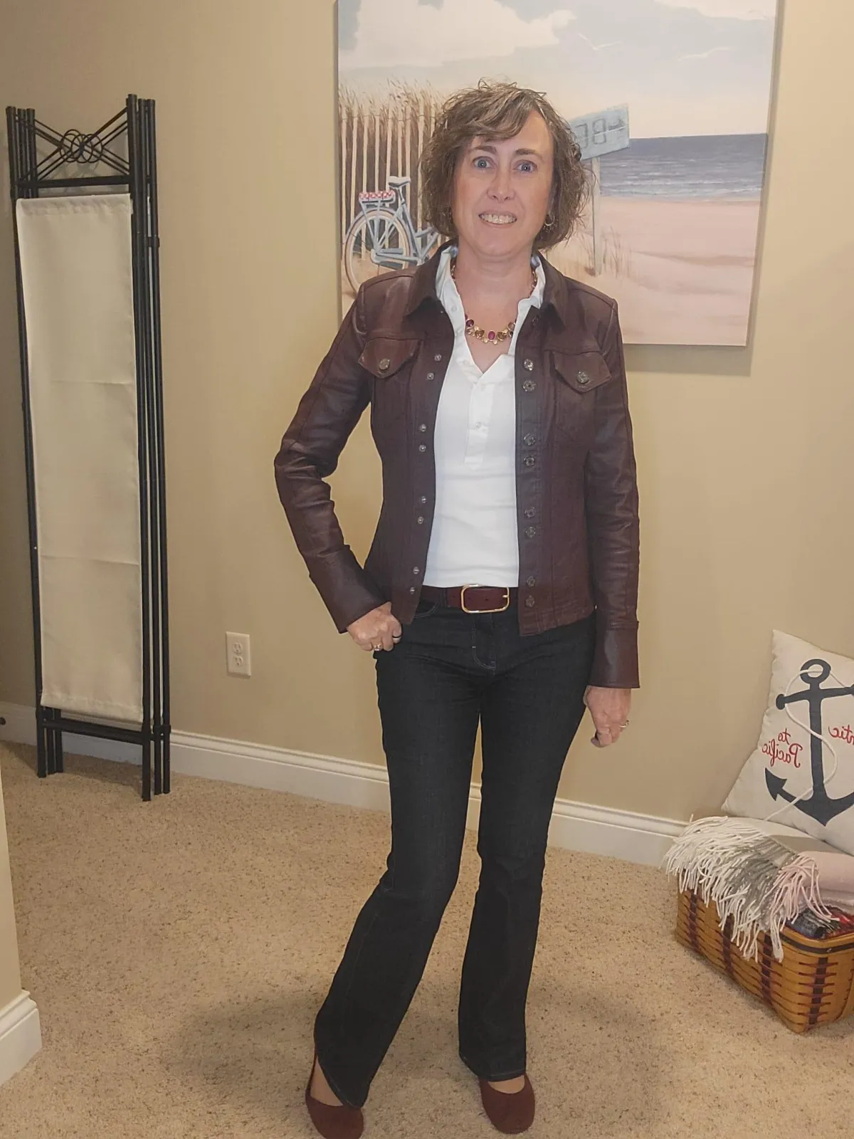 Jenn Whitacre wearing a WHBM pink cashmere-blend sweater layered over a white blouse with dark denim jeans, silver jewelry, and black boots. The blouse adds brightness at the neckline and hem, creating a soft yet refined look.