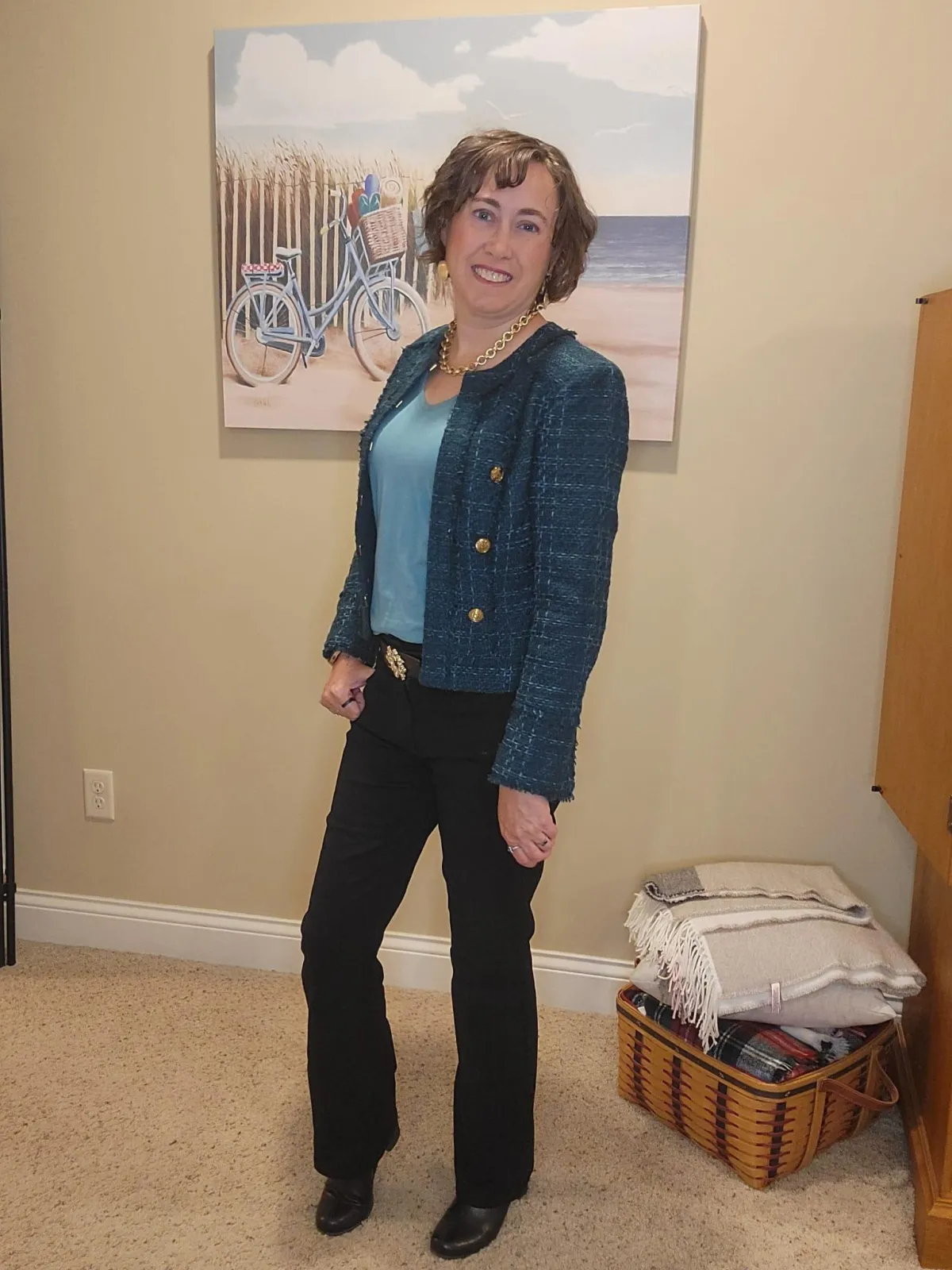 enn Whitacre wearing a WHBM teal tweed jacket over a light teal v-neck top, styled with gold jewelry, black bootcut jeans, and black boots for a chic and polished look.