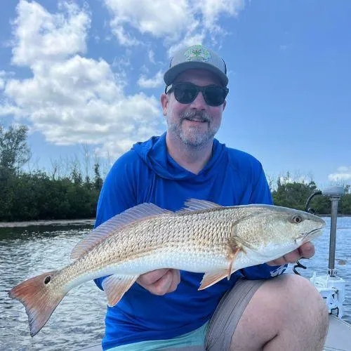 “Happy angler kneeling on the boat with a freshly caught redfish during an inshore fishing charter in Gulf Shores, Alabama with Captain Tanner.”