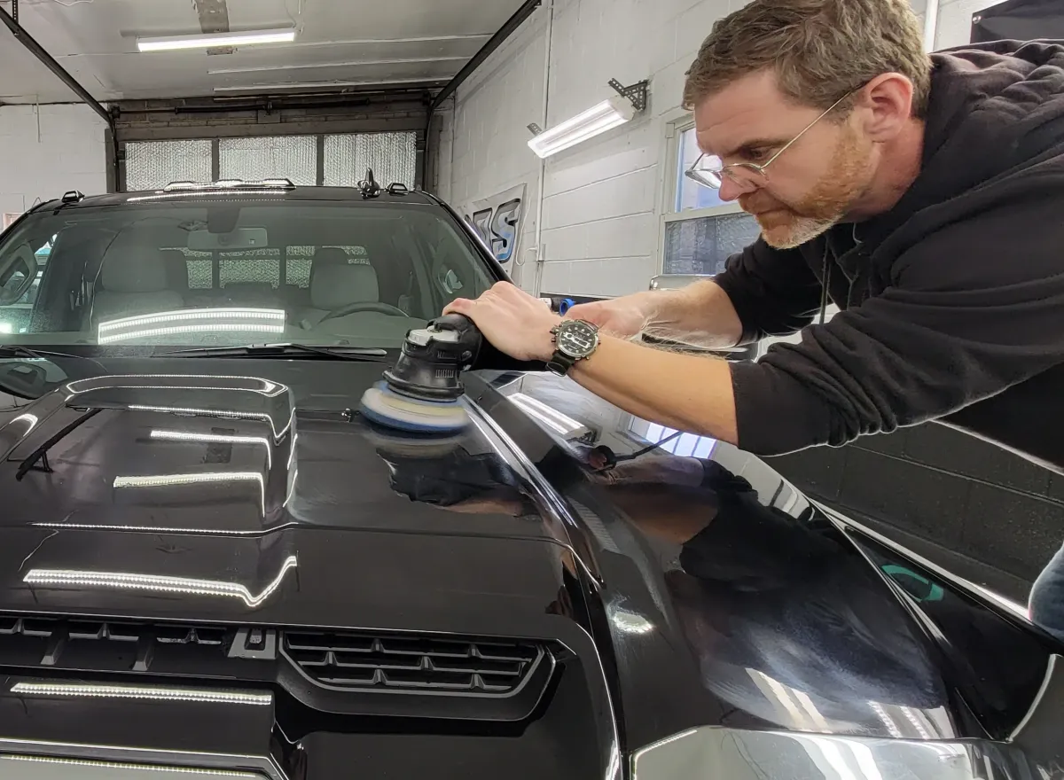 Applying ceramic coating to a glossy black car hood, enhancing shine and protection in Roanoke.