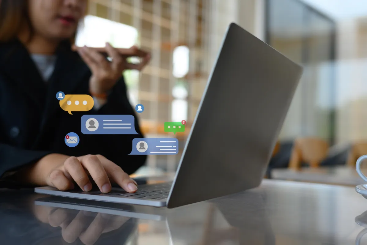 Woman talking on cell phone while typing on laptop