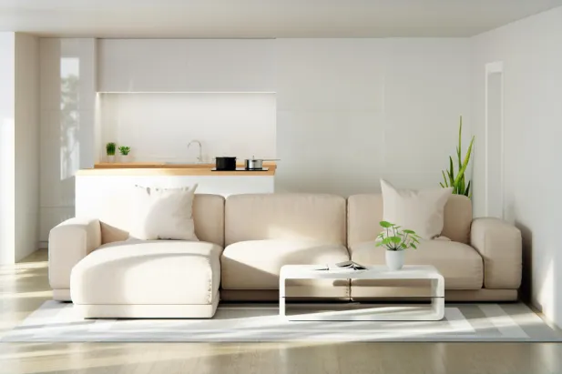 A contemporary living room with white furniture and an adjoining kitchen.
