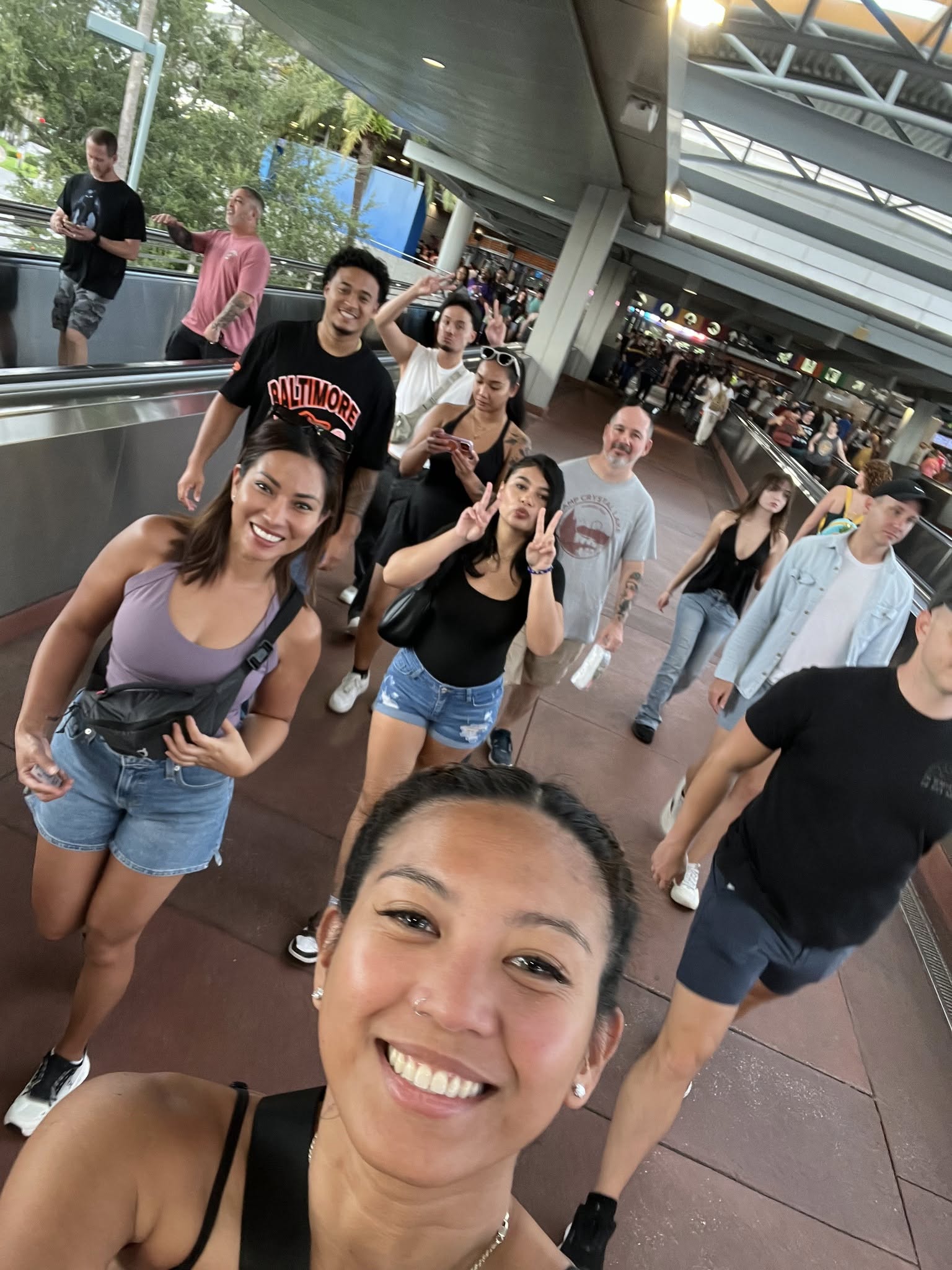 Neslyn practicing yoga on a rooftop at sunset in Santorini, white buildings and blue domes behind her. She holds a graceful pose, silhouetted against the glowing sky. 1:1 aspect ratio.