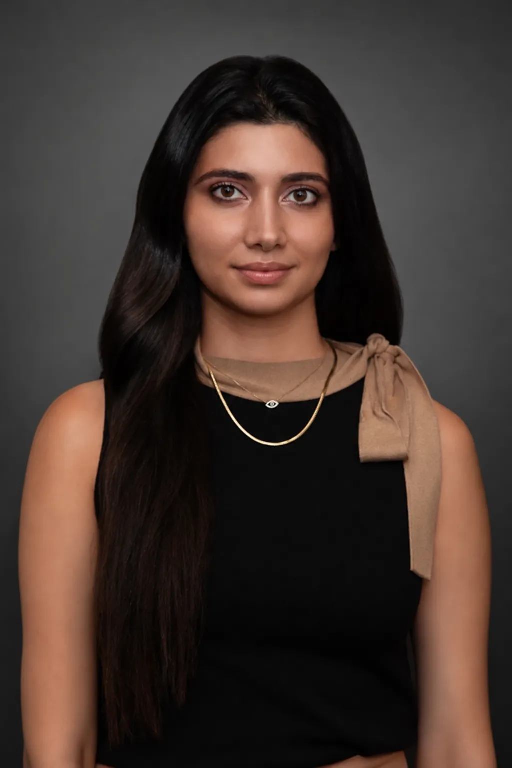 Portrait of a young woman with long dark hair, wearing a black top and a tan scarf, representing a member of the Maryam Jahedi Law Firm P.C. team, emphasizing professionalism and legal expertise.