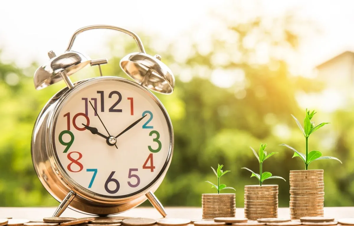 Time and money concept with alarm clock and stacked coins growing into plants, symbolising financial growth, strategic planning, and long-term business success through coaching.