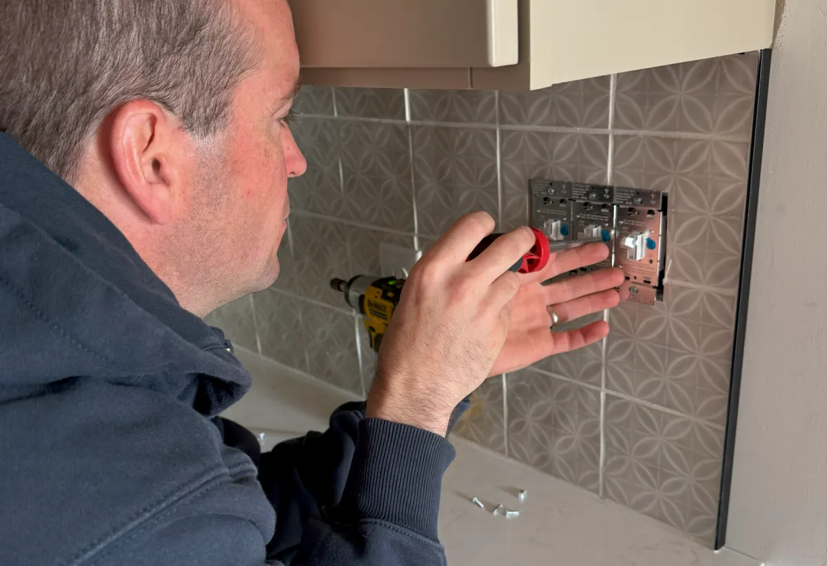 Old Saybrook CT electrician performing residential electrical work, installing modern light switches in a kitchen backsplash. Expert in kitchen wiring, lighting control systems, and smart home electrical upgrades. Serving residential and commercial clients along the Connecticut shoreline with professional, licensed electrical services.