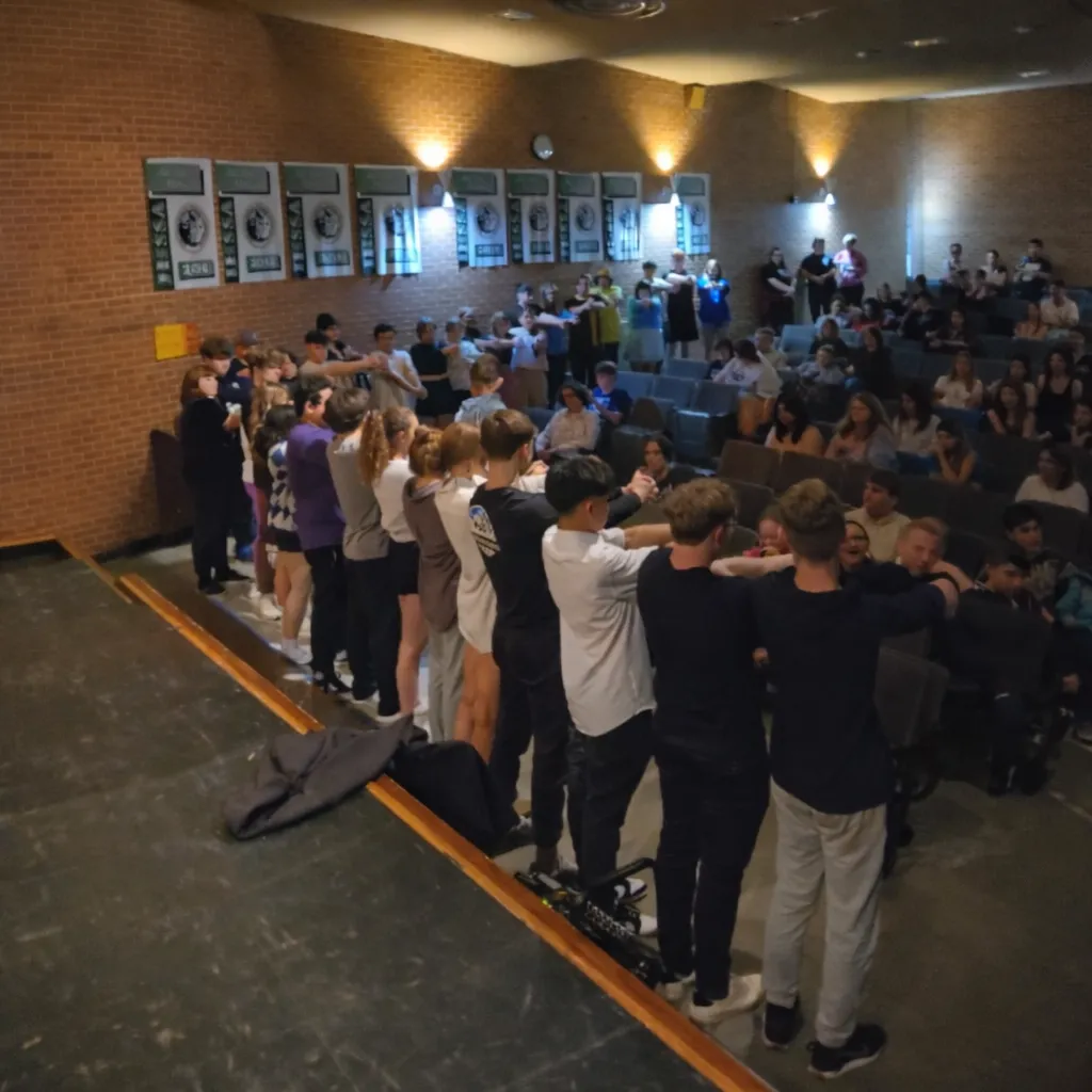 College students standing and participating in a live stage performance with Elijah Edwards