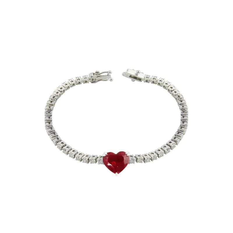 An 18k white gold tennis bracelet designed with a heart-shaped ruby charm