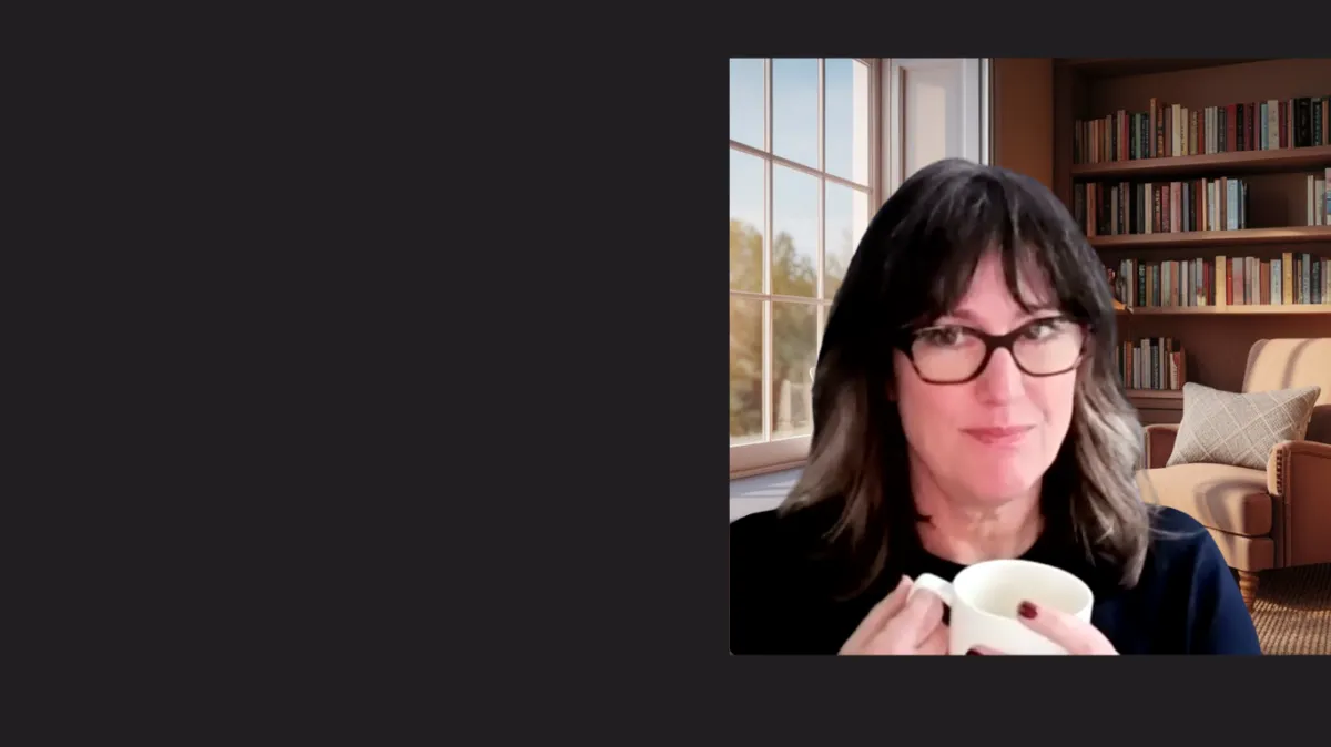 Person smiling looking off to the side, with brown hair and wearing glasses is sitting and holding a coffee mug.