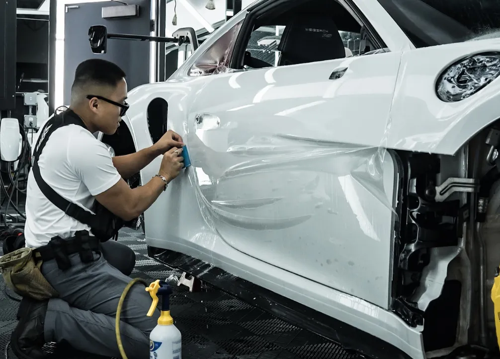 Man applying PPF on a white car