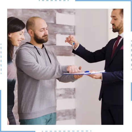  A realtor hands keys to a man and woman signing papers, symbolizing receiving down payment assistance for their new home.