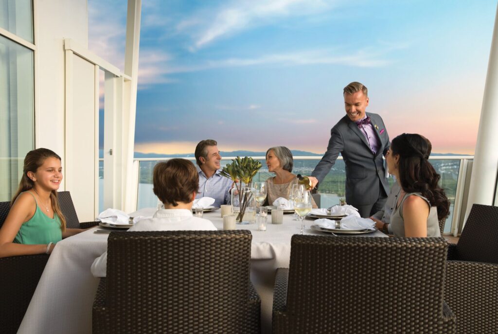 A family enjoying dinner sitting on their cruise ship balcony.