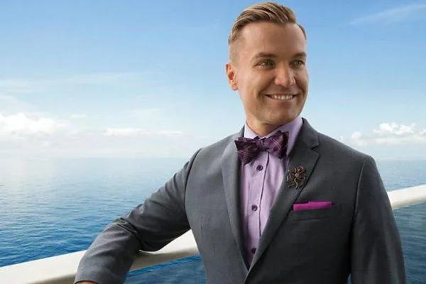 A cruise concierge standing by the railing of a cruise ship, overlooking the ocean.