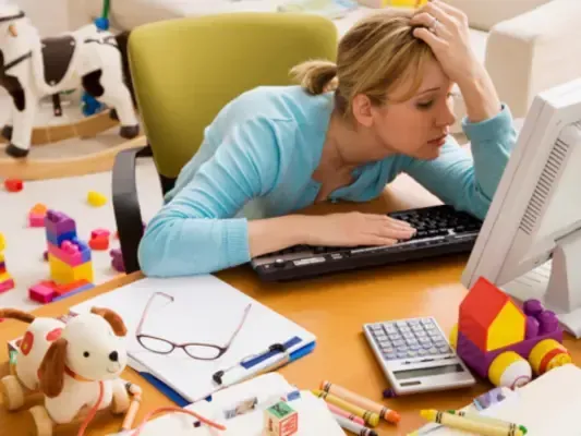 Stressed business owner sitting at a desk with paperwork and a calculator, looking overwhelmed