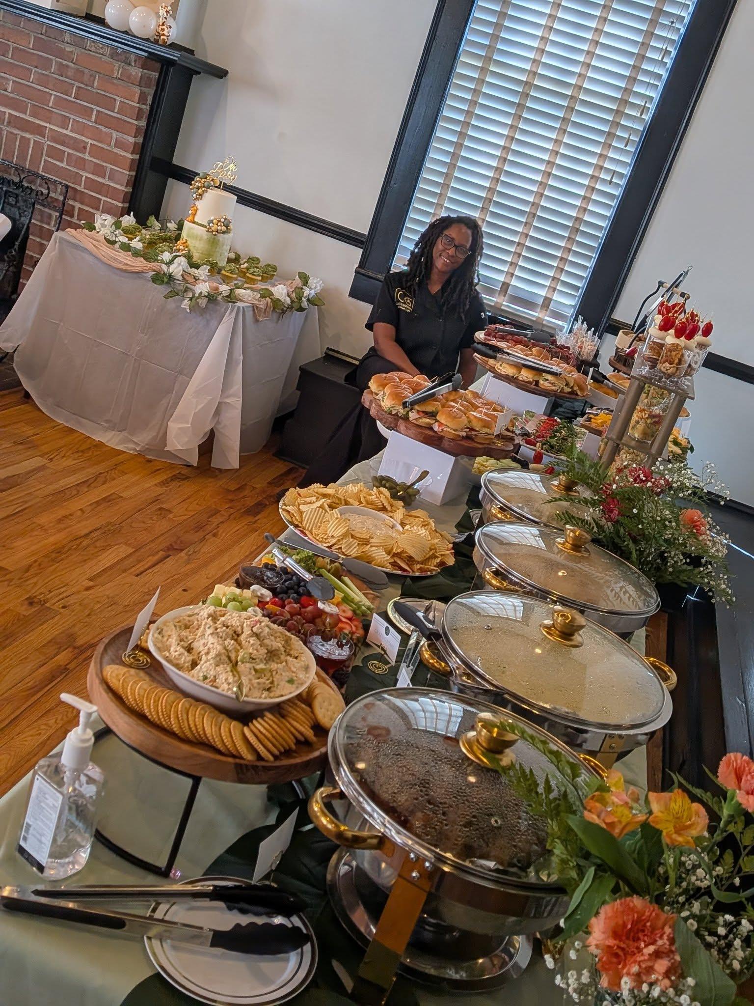 Catering display featuring croissant sandwiches filled with chicken salad, garnished with decorative toothpicks, and accompanied by assorted sliders, charcuterie, and fresh fruit cups, showcasing Castle Gardens ILM's elevated culinary offerings for events.
