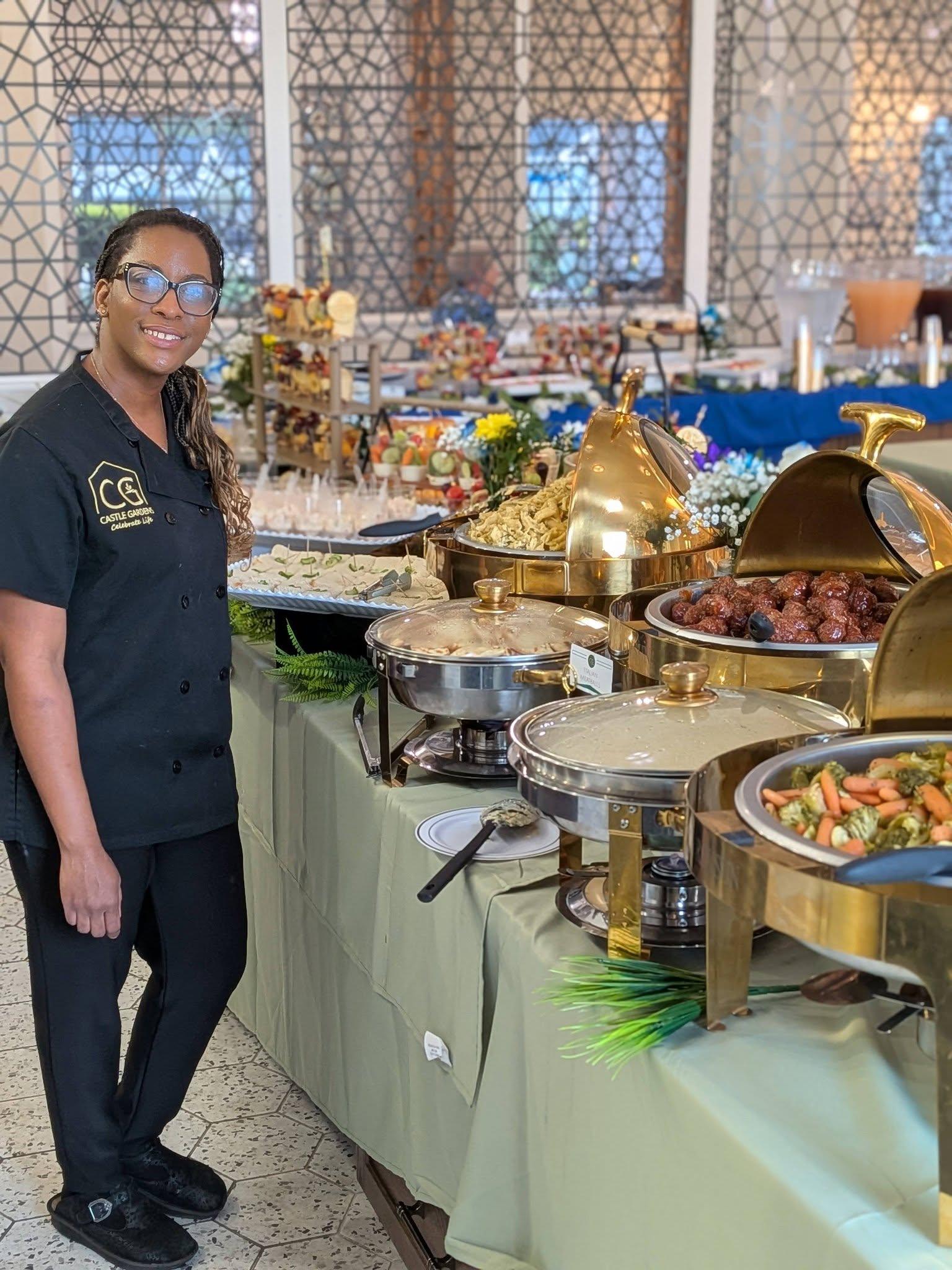 Catering display featuring croissant sandwiches filled with chicken salad, garnished with decorative toothpicks, and accompanied by assorted sliders, charcuterie, and fresh fruit cups, showcasing Castle Gardens ILM's elevated culinary offerings for events.