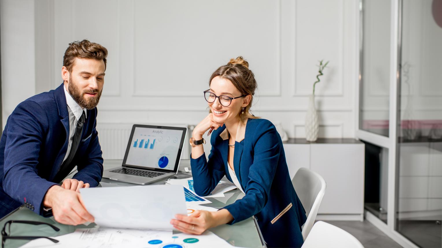 Confident business owner sitting with an accounting professional, reviewing financial information on a laptop