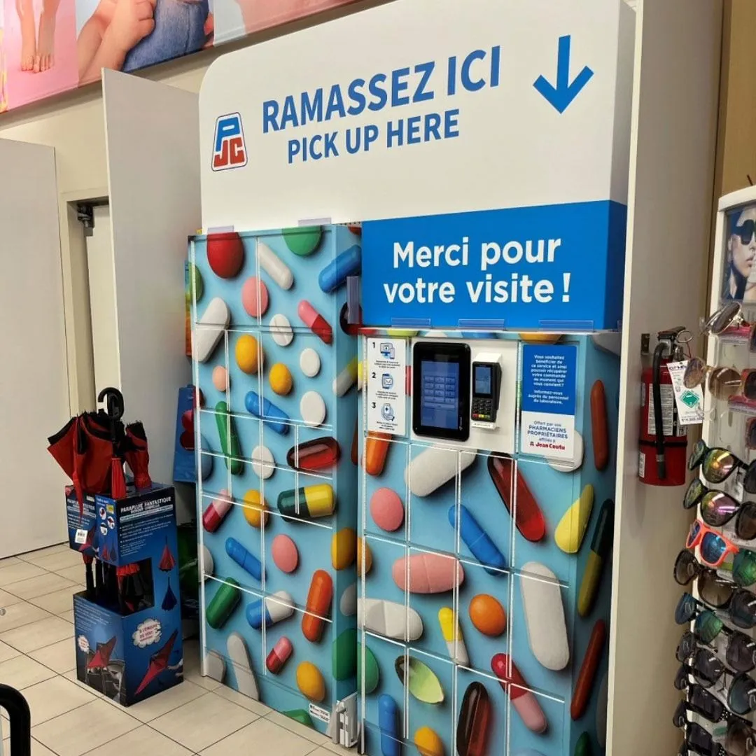 Mur de casiers intelligents Sir Steward décoré de pilules chez Jean Coutu, zone « Ramassez ici » pour ordonnances.