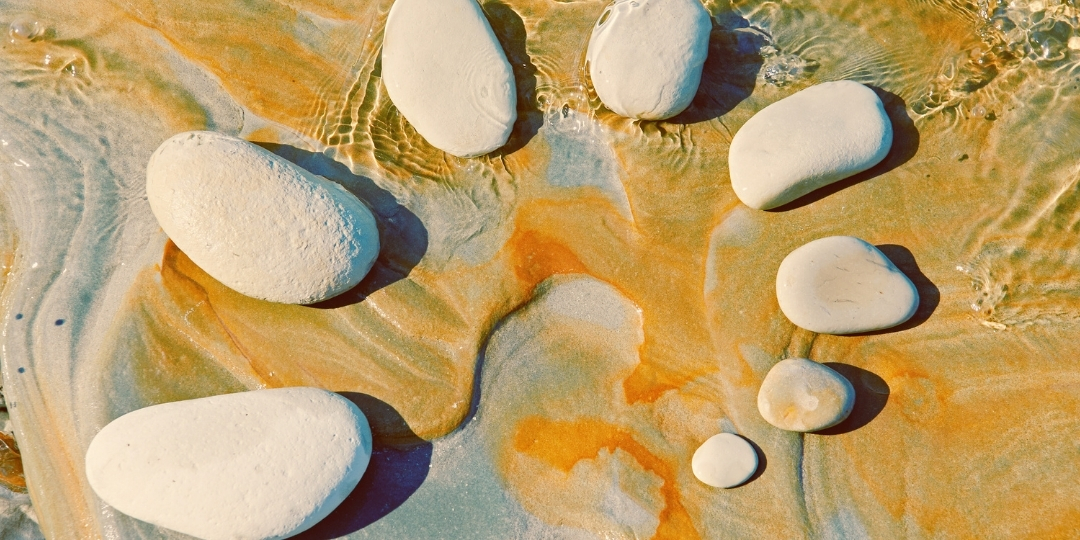 Smooth white stones arranged on a textured surface with swirling golden and earthy tones.