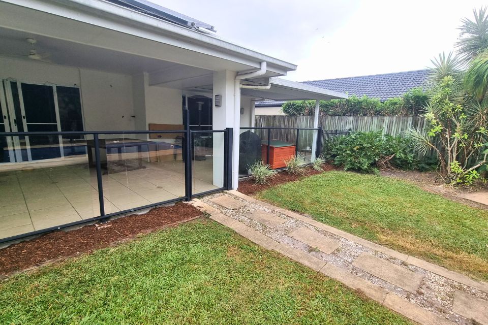 Overgrown weeds and vines surrounding the house wall before the Buderim backyard clean-up