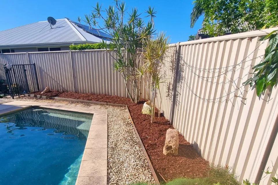 Low-maintenance poolside landscaping with mulch, garden edging and established plants