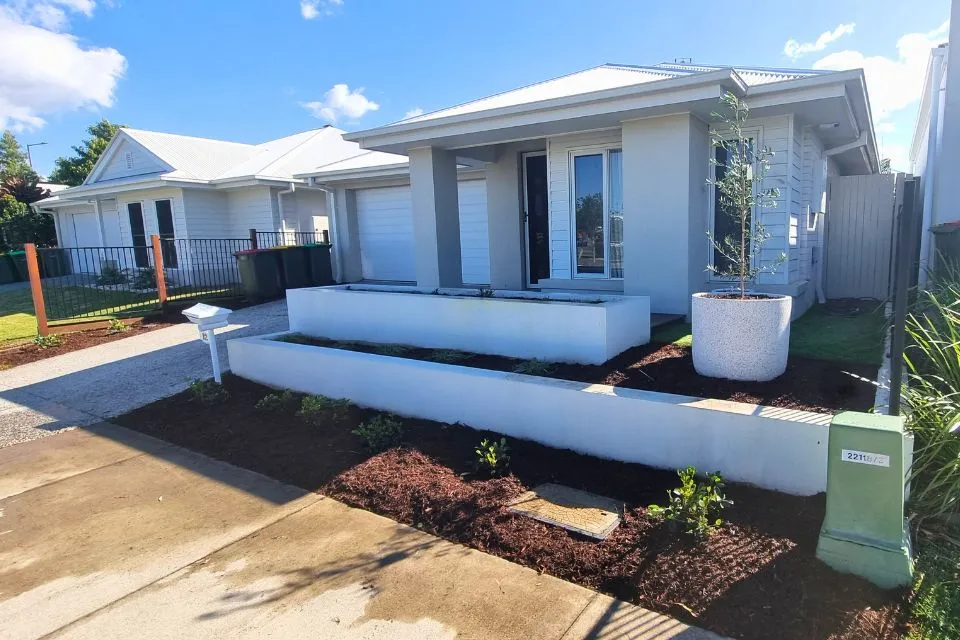 Landscaped front garden with raised garden beds, planting and fresh mulch