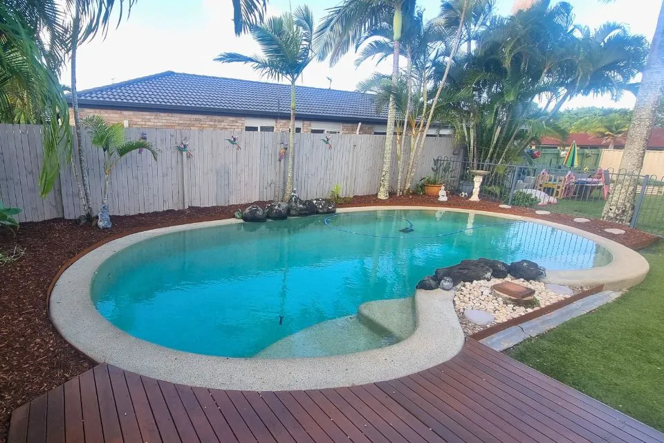 Poolside garden makeover in Minyama featuring fresh mulch, timber decking, steel garden edging and tropical garden beds