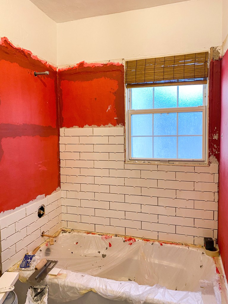 man in orange and black jacket and blue denim jeans jumping on gray concrete floor under