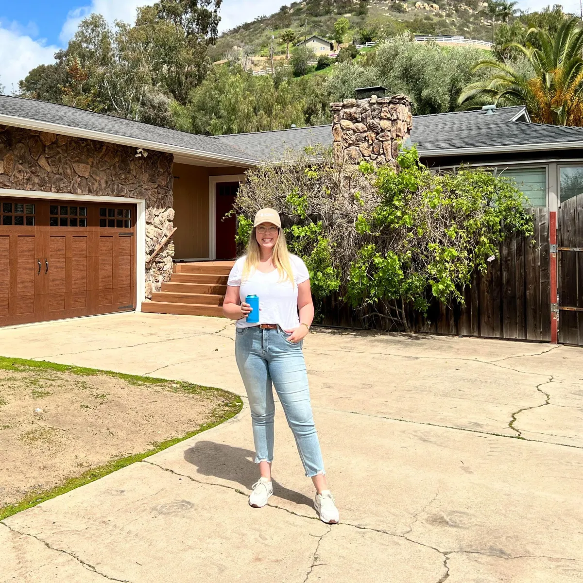 woman wearing jeans and white t shirt standing in front of a single story house
