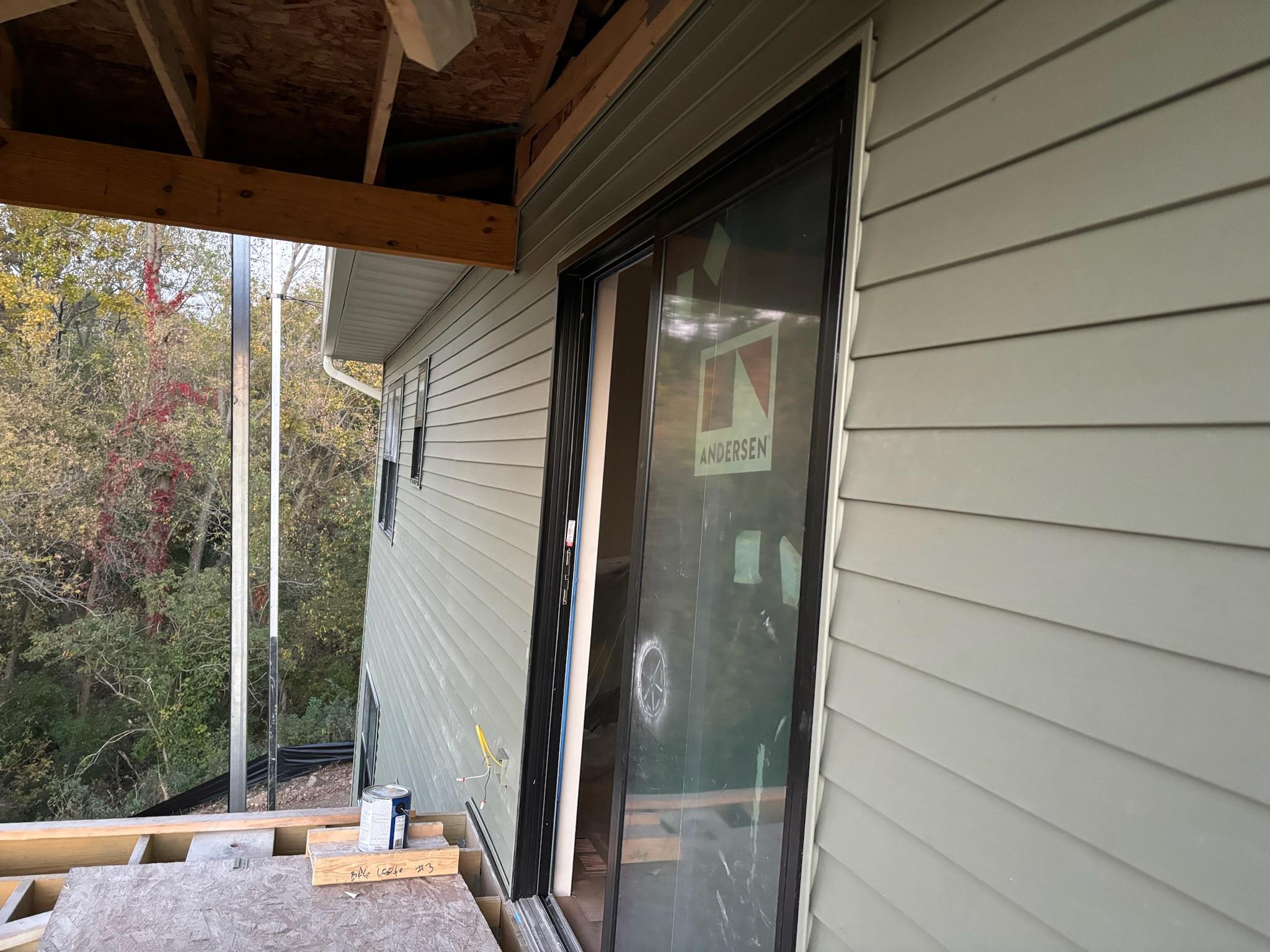 New siding and sliding glass door installation on a residential property.