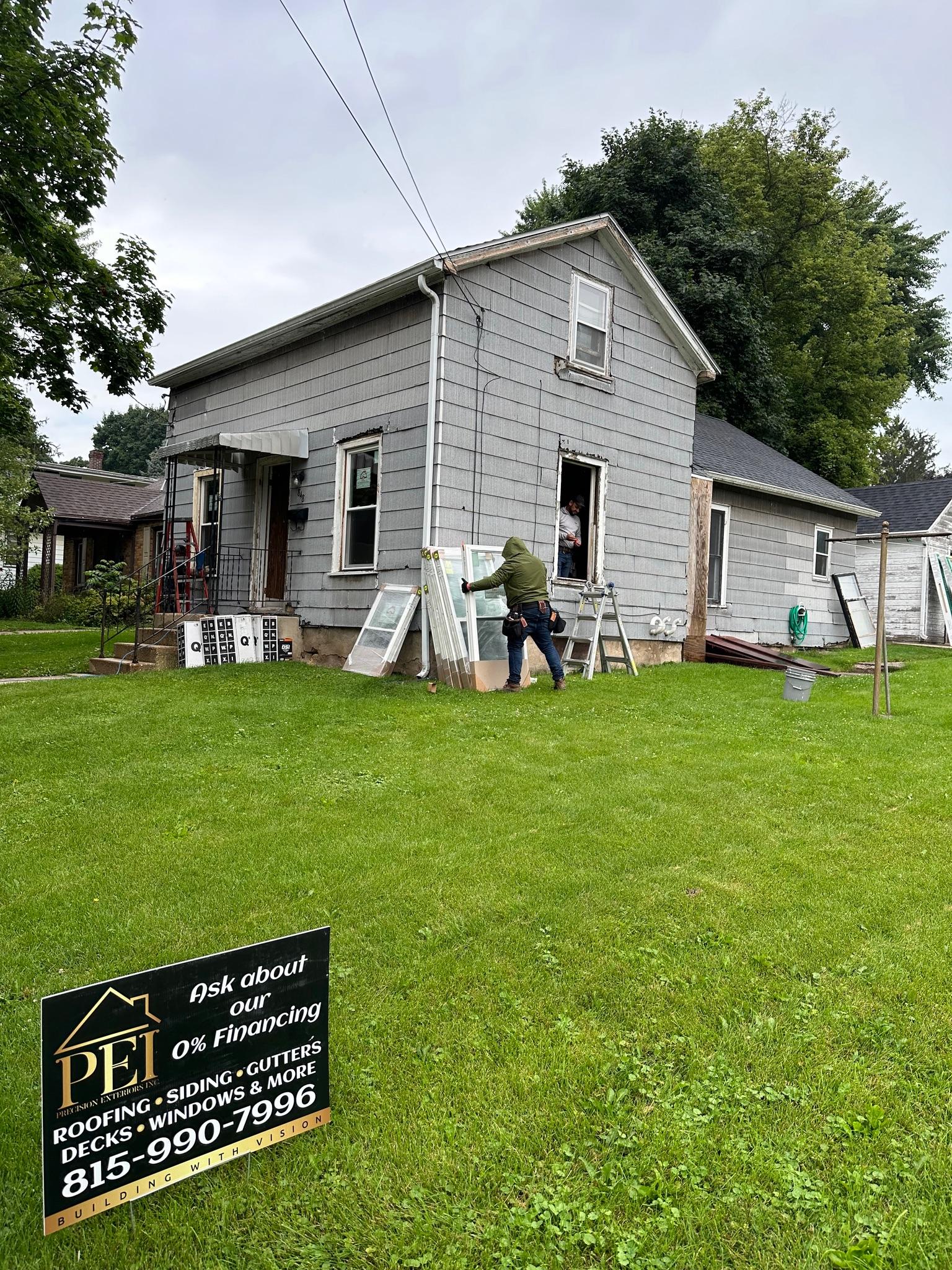 New replacement windows installed on a home with gray vinyl siding.