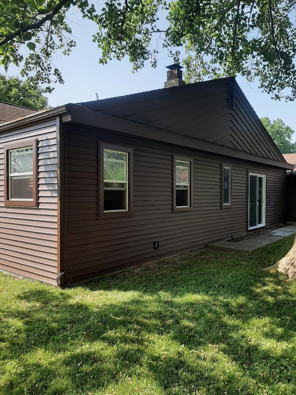 A residential home exterior showcasing newly installed dark brown horizontal siding with matching dark brown trim on the walls and gable. The project features newly integrated single-hung windows and a white-trimmed sliding glass patio door, completed by Precision Exterior Inc., serving Lena, IL and surrounding areas.