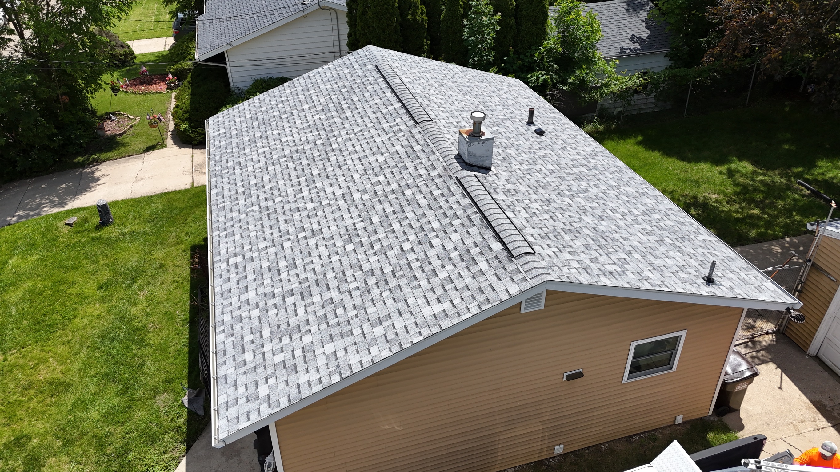 Aerial view of a completed residential roofing project surrounded by yard.