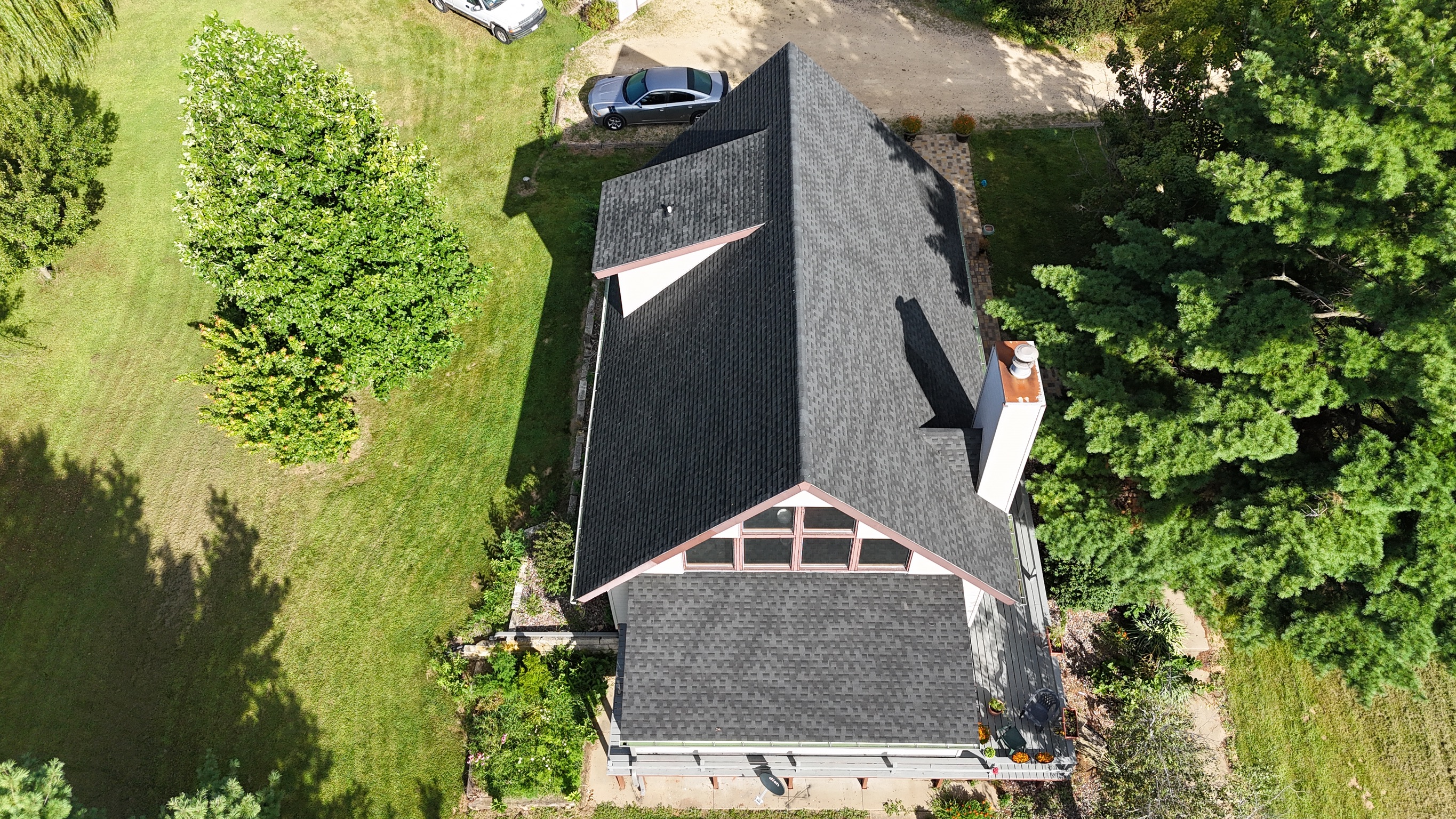Finished asphalt shingle roof on a suburban home surrounded by trees.