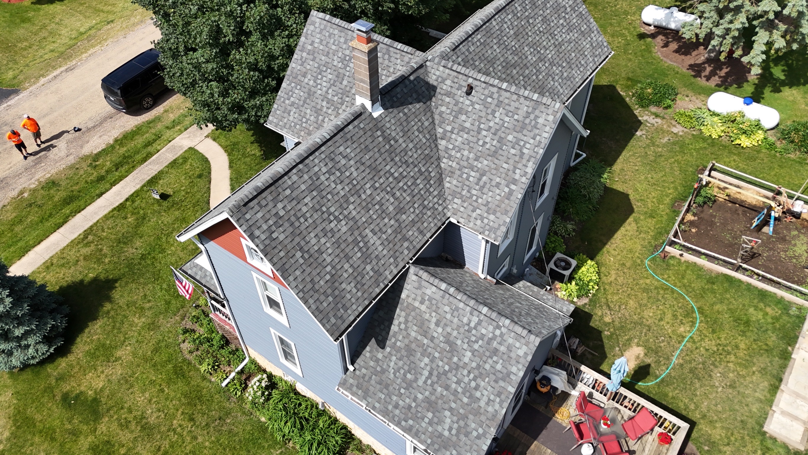 Aerial view of a multi-gabled home with a newly replaced shingle roof by Precision Exteriors Inc.