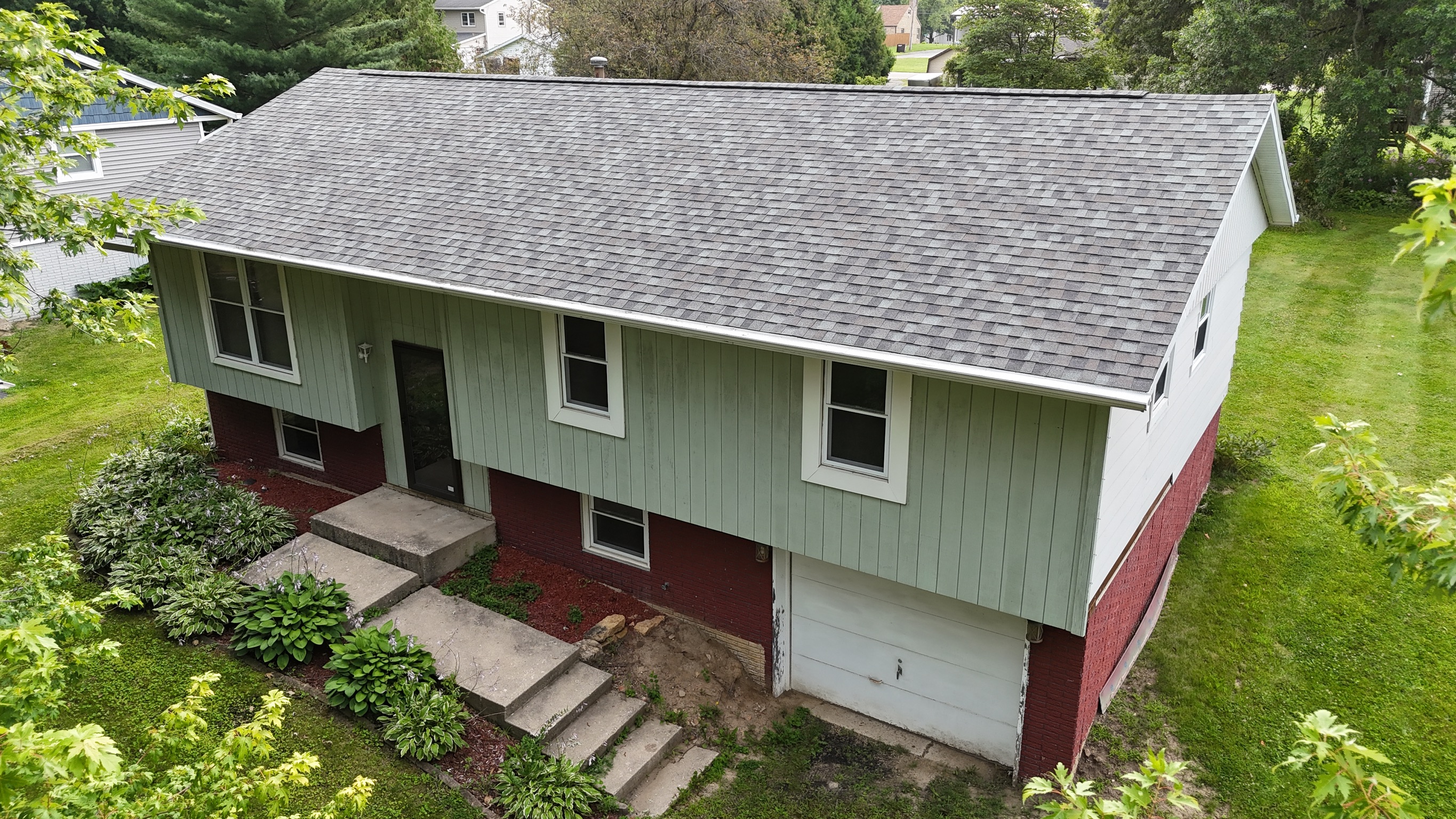 Finished residential roof installation with new gray architectural shingles.