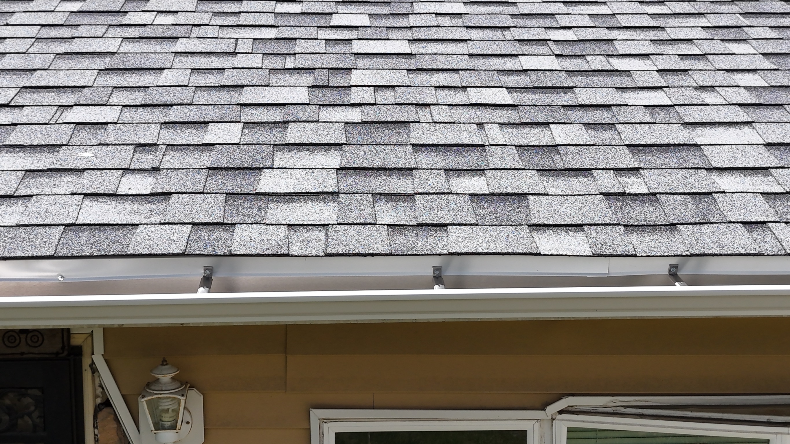 Drone perspective of a newly installed gray shingle roof on a suburban home.