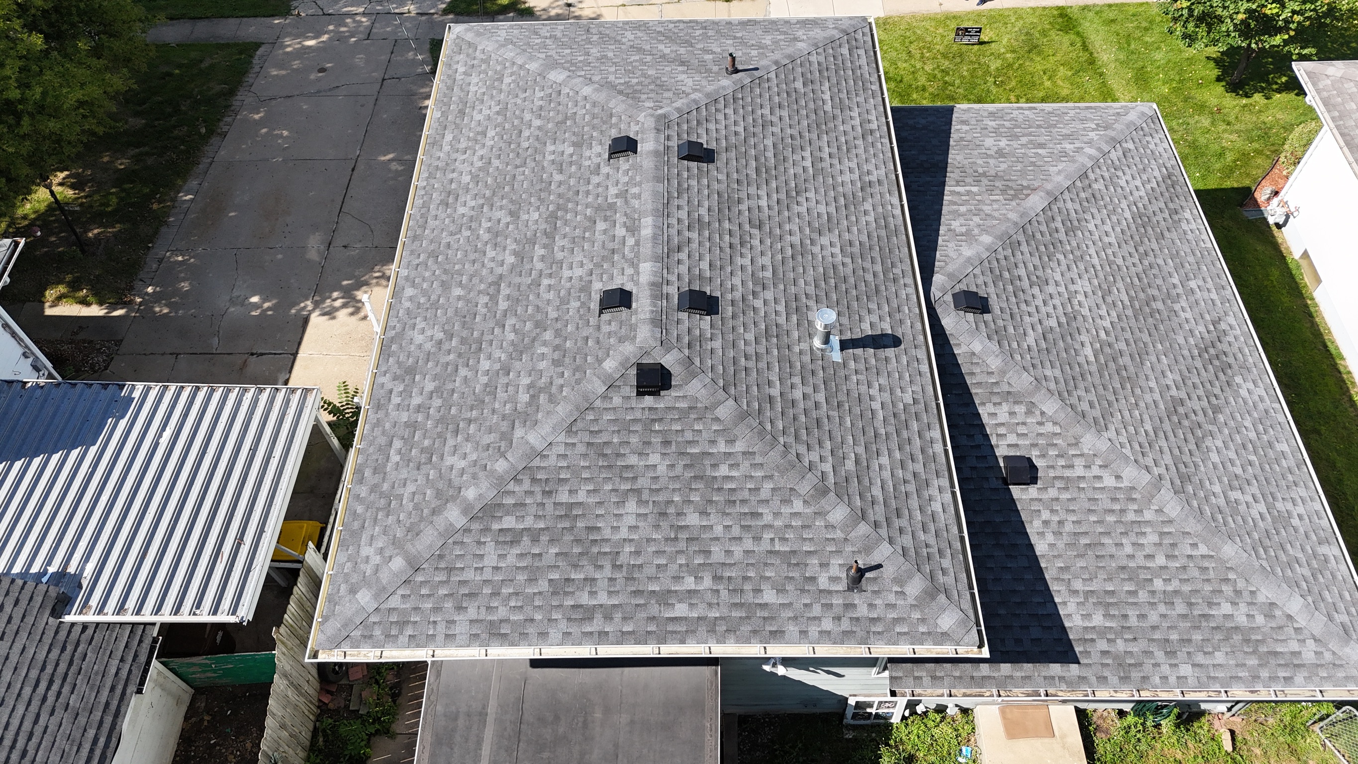 Drone view of a finished asphalt shingle roof on a two-story house.