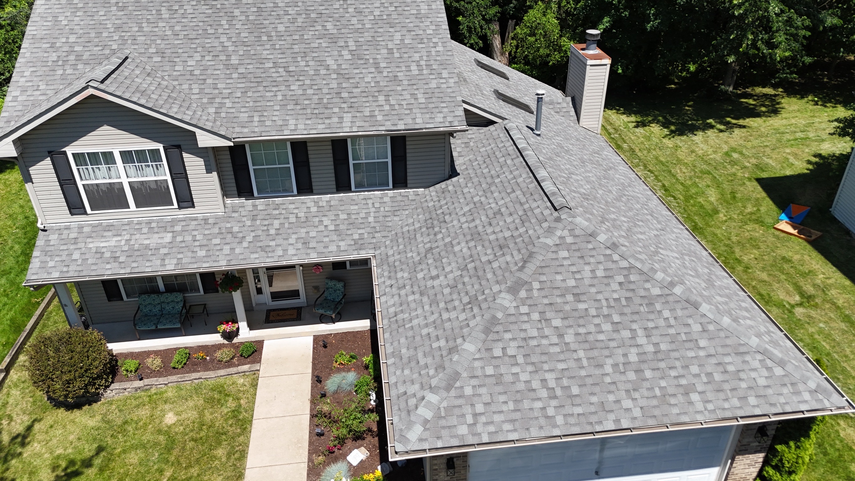 Finished asphalt shingle roof on a two-story suburban home.