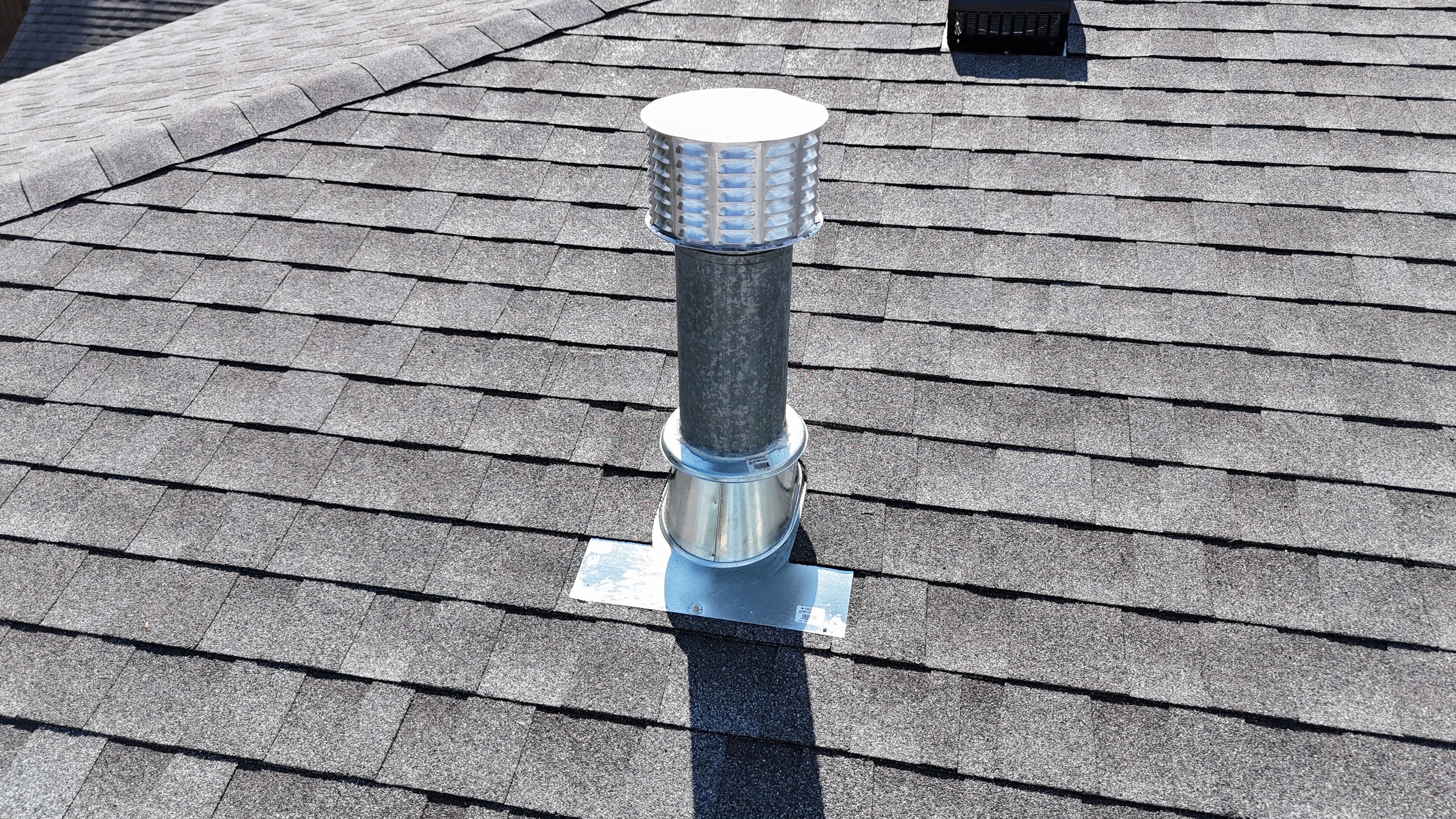 Close-up of a newly installed roof pipe flashing boot on a shingle roof.