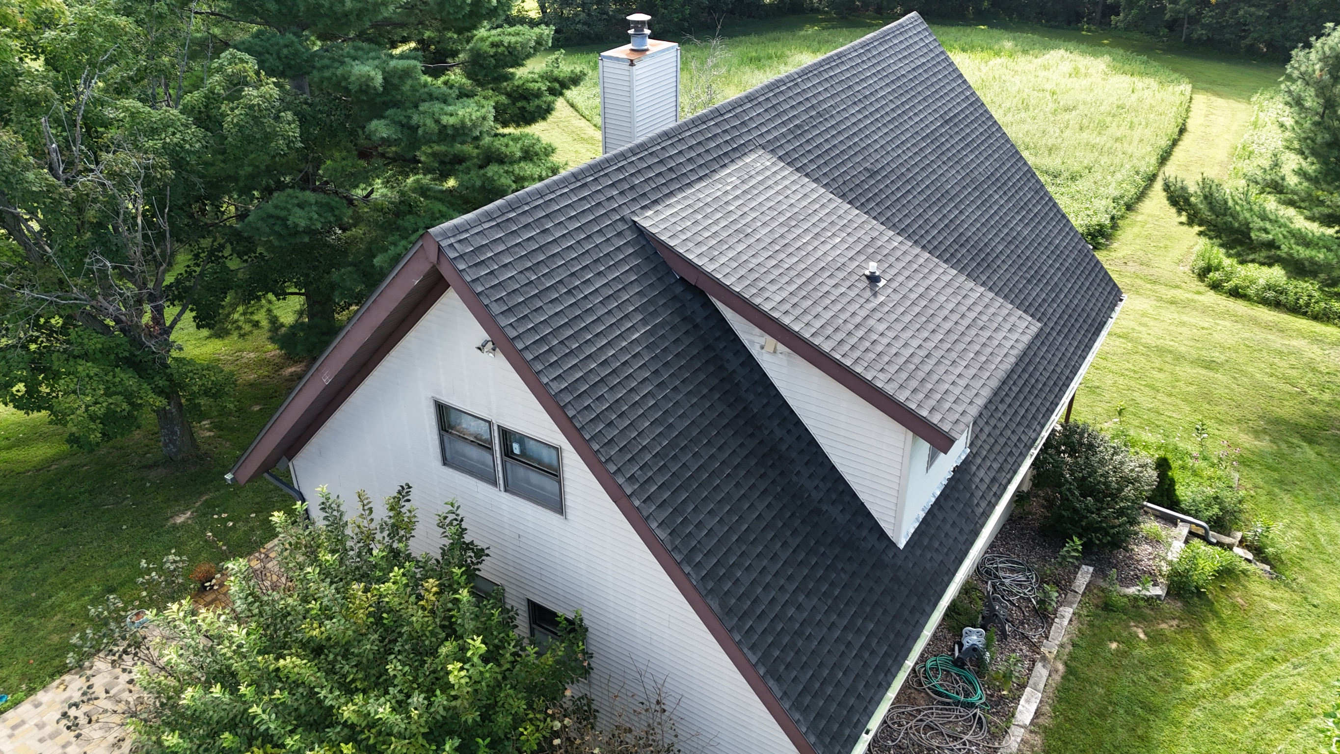 Drone view of a gray asphalt shingle roof replacement on a suburban home.
