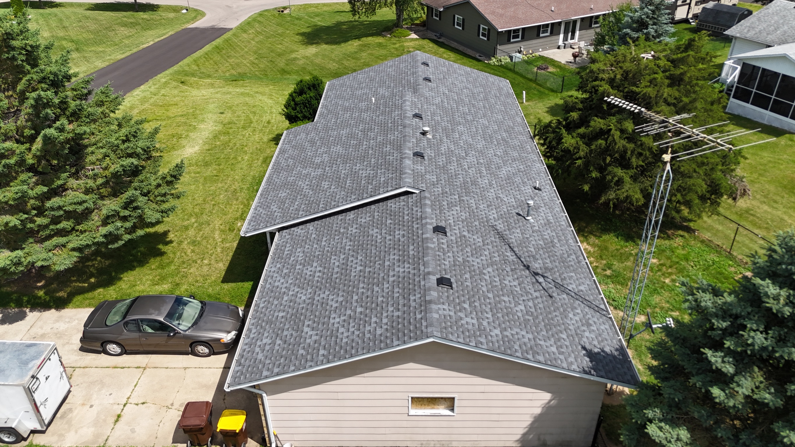 Finished asphalt shingle roof installation on a two-story house.
