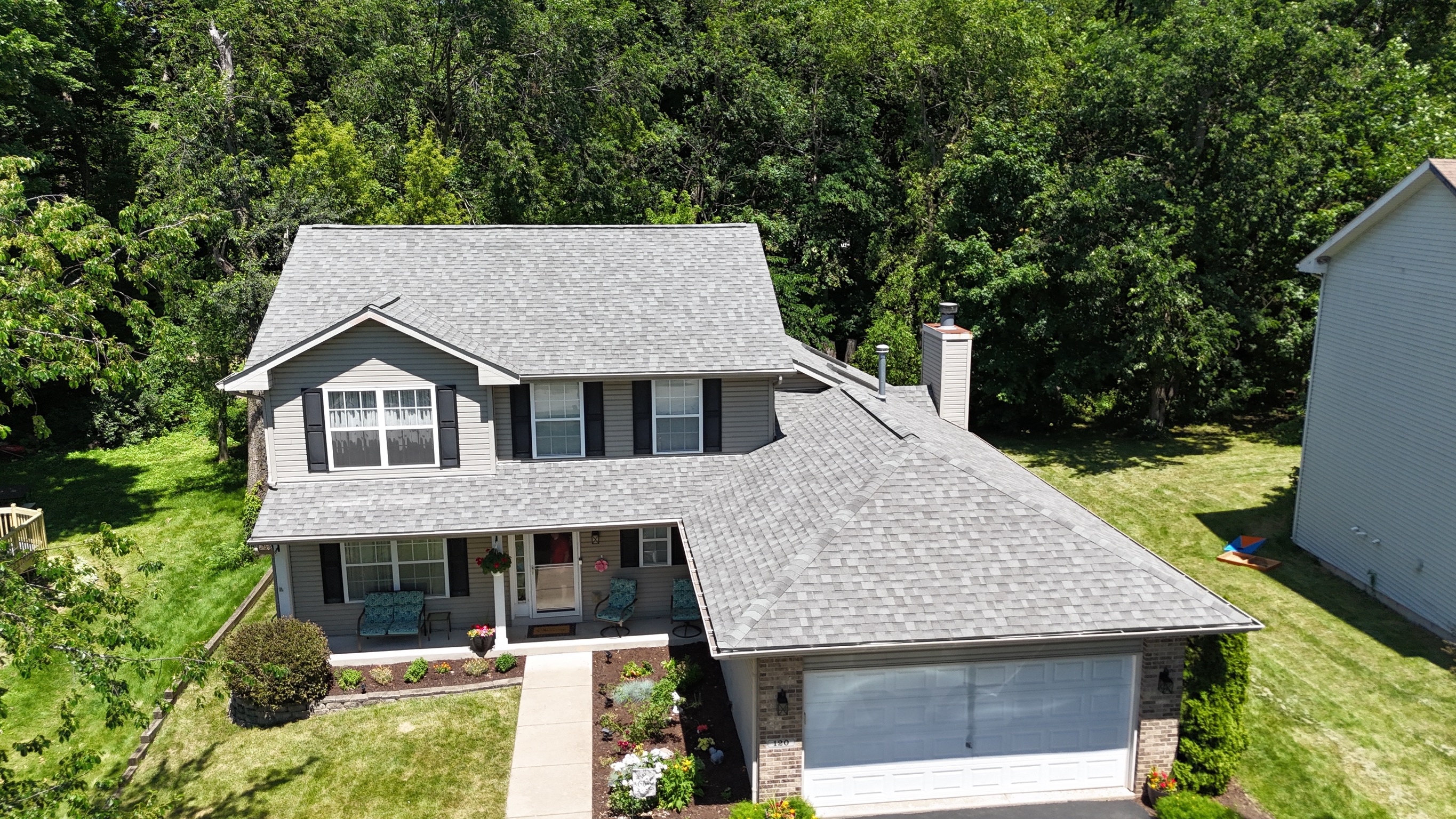 Drone view of a newly finished charcoal shingle roof on a two-story house by Precision Exteriors Inc.