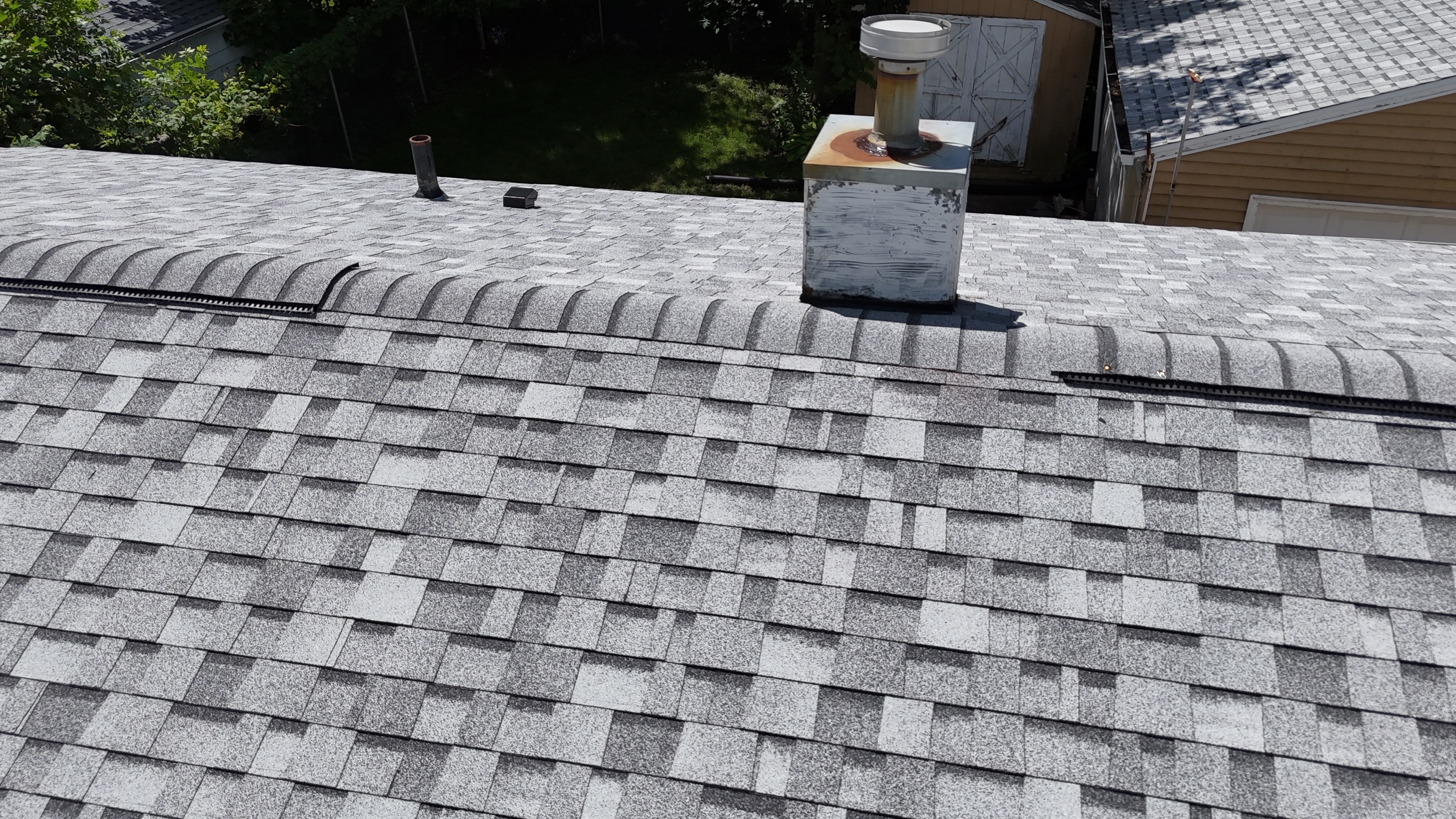 Detailed drone view of a clean roof valley and ridge shingle installation.