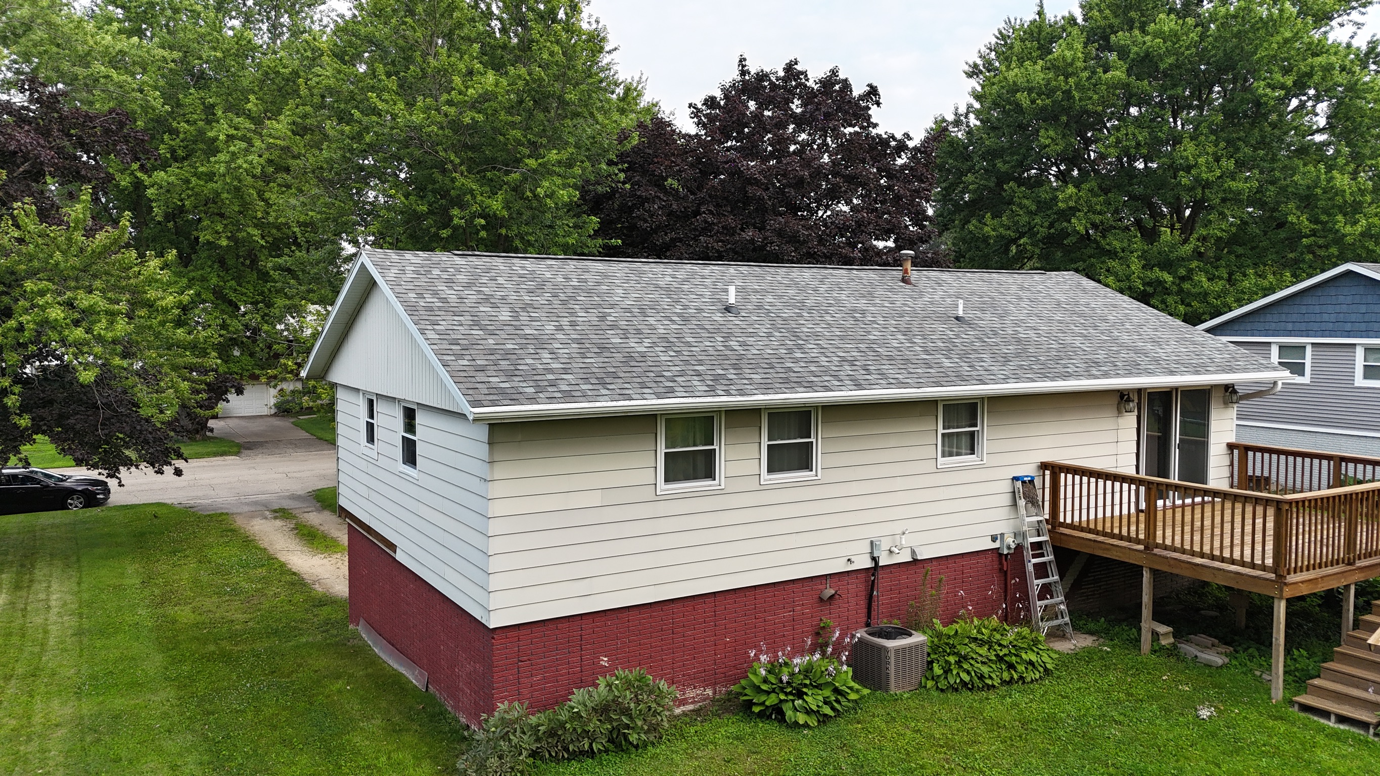 Completed light gray asphalt shingle roof on a suburban ranch house.