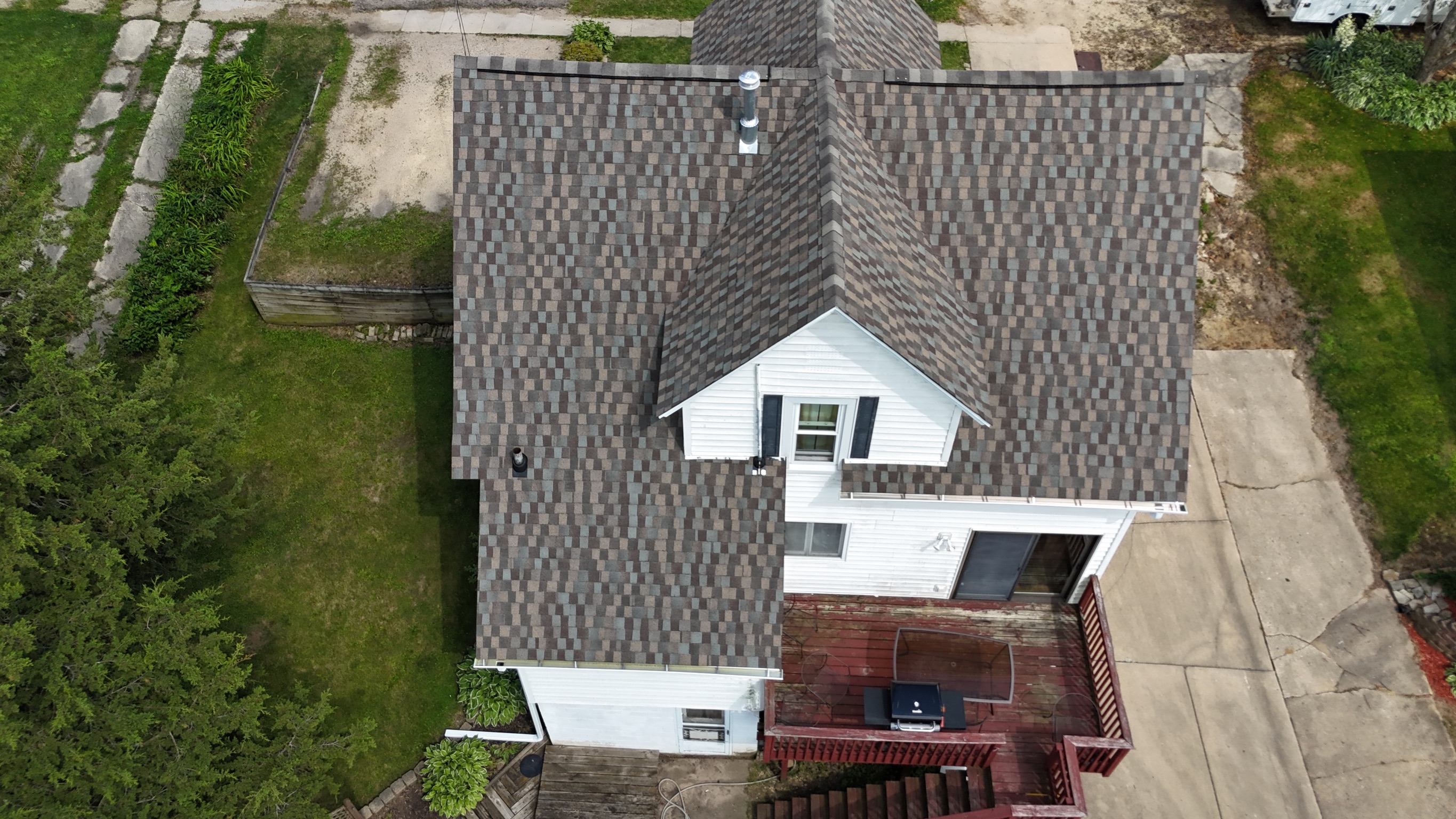 Aerial view of a completed residential roofing project with new dark gray shingles.