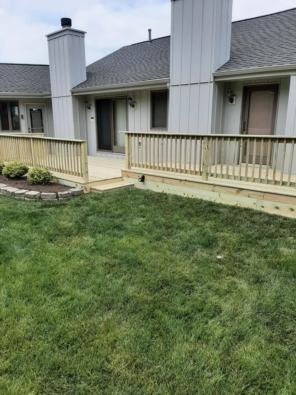 Custom multi-level pressure-treated wood deck with safety railings built on a grey siding house by Precision Exterior Inc.