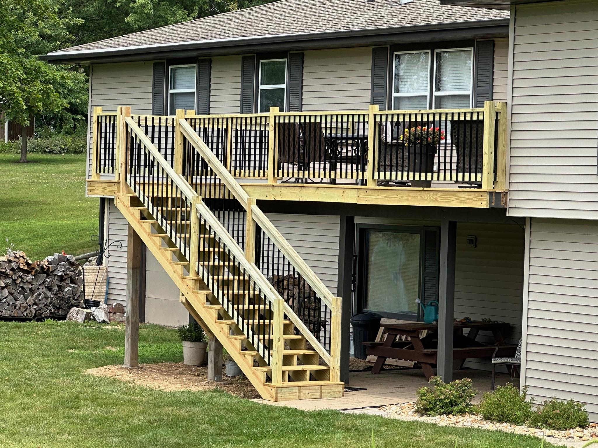 Custom elevated wood deck and staircase with black metal spindles built by Precision Exterior Inc. on a residential home in Lena, IL.