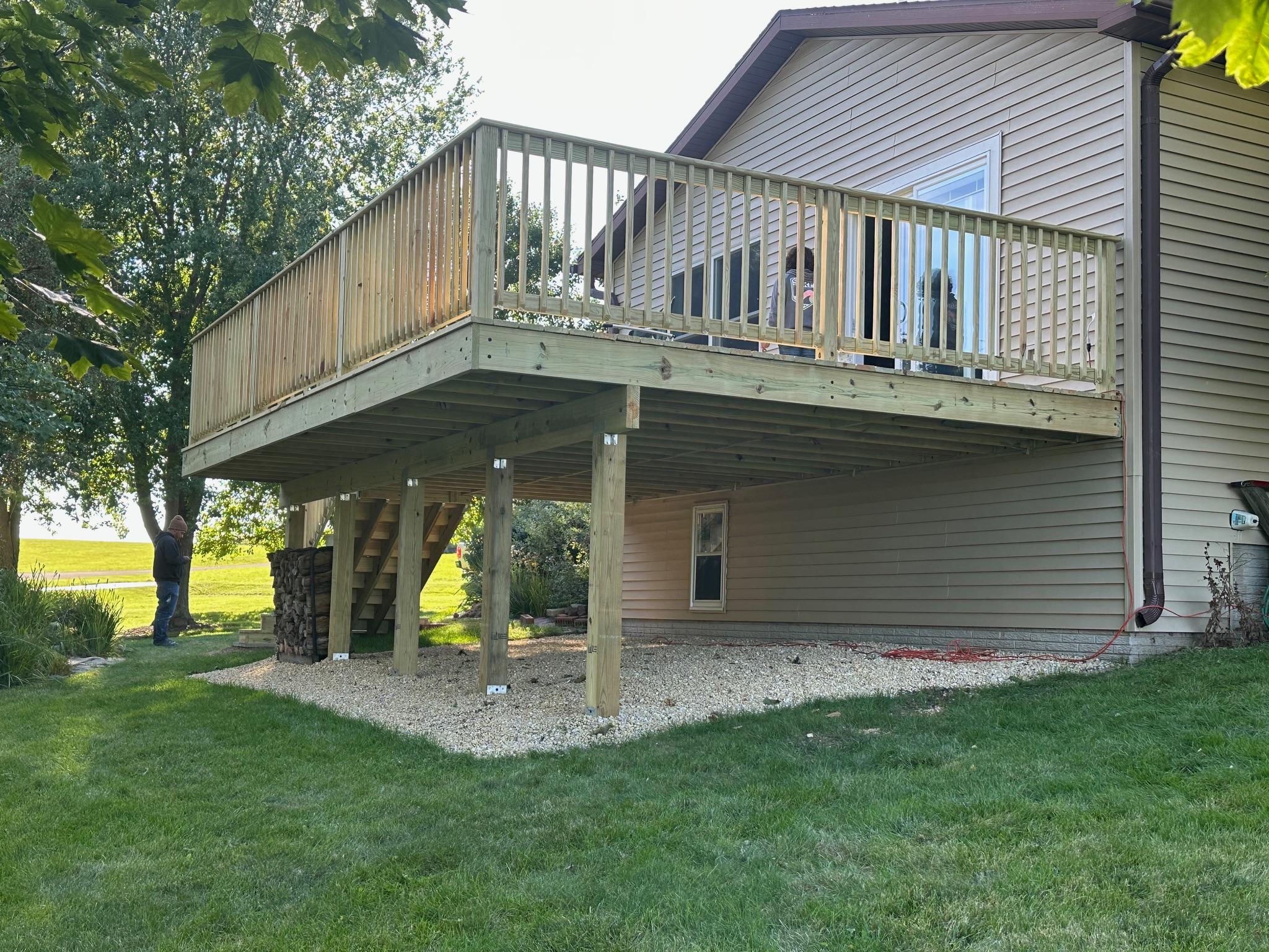 Large elevated pressure-treated wood deck and safety railing built on a residential home by Precision Exterior Inc. in Lena, IL.